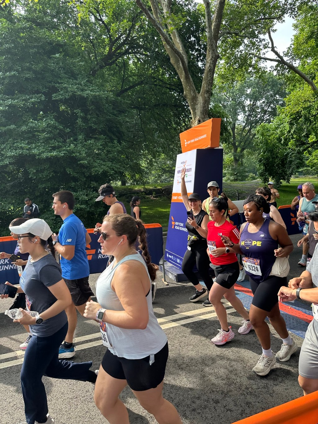 Starting line of Achilles Hope & Possibility Race in Central Park with people running past the starting line.